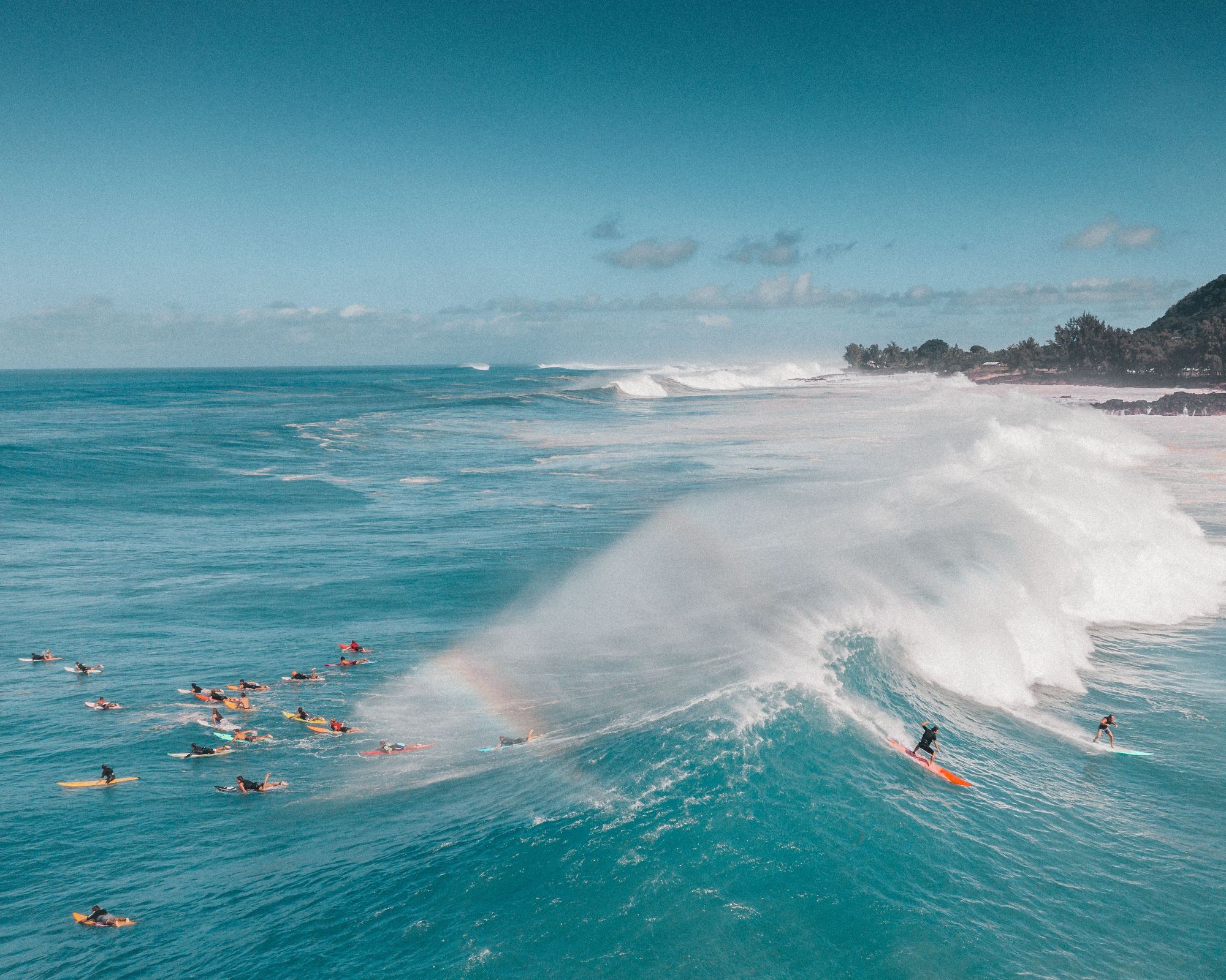 Surfers in the lineup as a big wave breaks at Waimea Bay