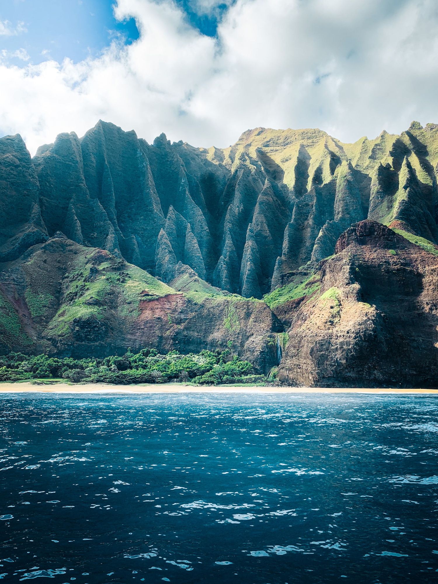 Na Pali Coast cliffs rising above clear blue water on Kauai