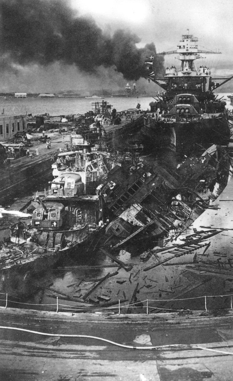 Wrecked destroyers and a battleship in a flooded drydock at Pearl Harbor after the attack