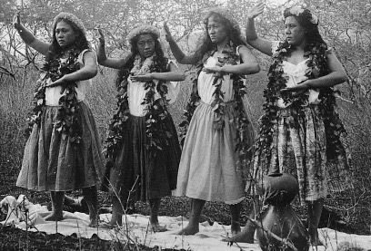 Four hula dancers wearing lei and skirts, photographed outdoors around 1900